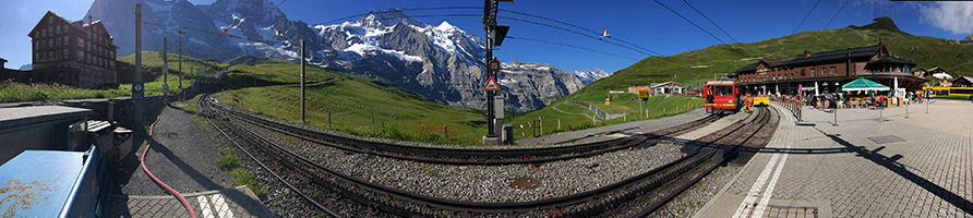 Blick auf Eiger, Mönch und Jungfrau vom Bahnhof Kleine Scheidegg aus gesehen. Rechts im Bild die Jungfraubahn auf dem Weg nach oben. Mitte oben das Ziel der Bahn: das Jungfraujoch. Ganz rechts die Wengernalpbahn Richtung Grindelwald.